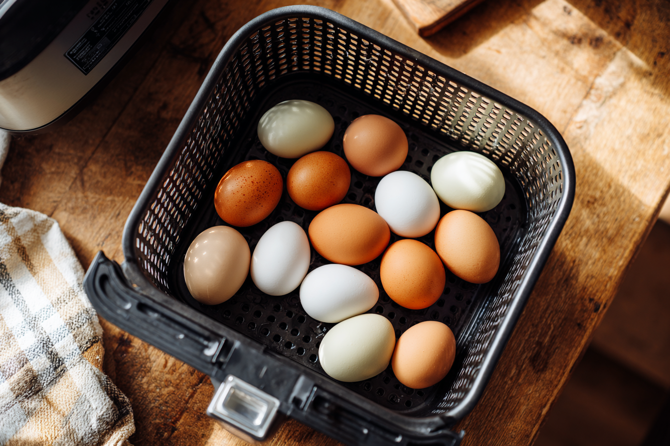 white and brown eggs in an air fryer basket