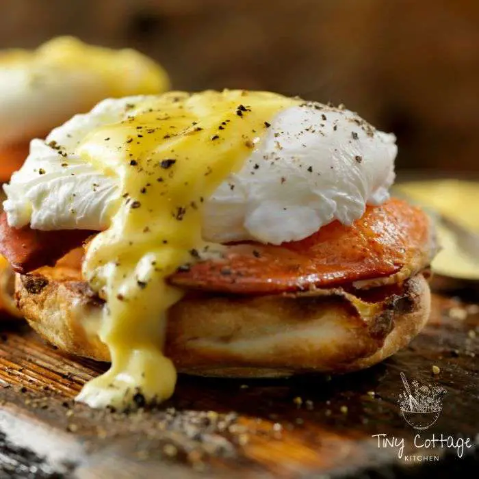 eggs benedict close up . poached egg on top of toasted english muffin, bacon , covered in hollondaise